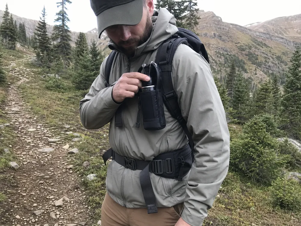 Bear spray chest holster worn in field position — showing chest carry access advantage over hip carry