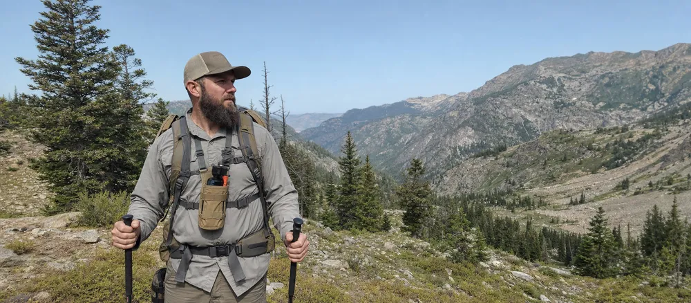 Backcountry hunting guide wearing bear spray chest holster in bear habitat terrain
