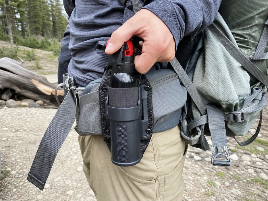 SOHAPI hiking holster attached to a loaded pack hip belt, showing the abrasion-reinforced clip contact zone and rotational clip system