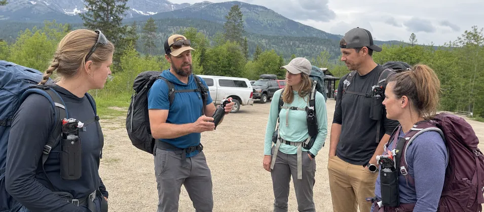 Wilderness outfitter guide service equipping clients with bear spray holsters for multi-day trips