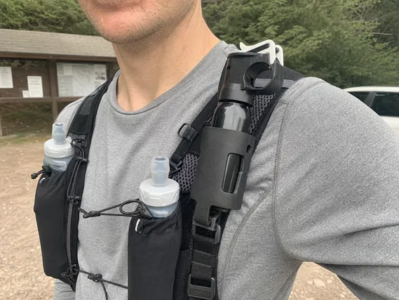 Bear spray running holster mounted on running vest shoulder strap