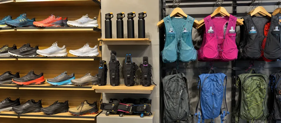 Trail running specialty retail store with bear spray and holster on display alongside footwear and hydration vests