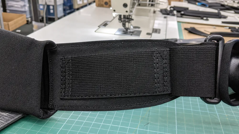 Reinforced abrasion zone on bear spray holster webbing at pack frame contact point