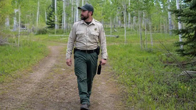 Wildlife management ranger with bear spray in field