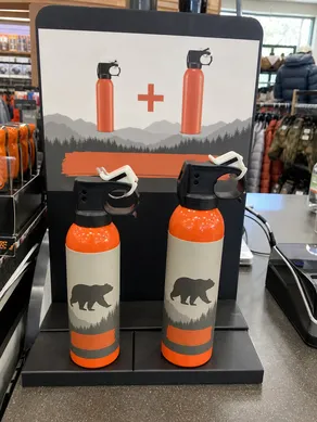 Retail bundle program with orange training bear spray canister as point-of-sale add-on alongside live product